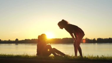 Eğitim sırasında arkadaşına yardım eden bir kızın silueti. Kadın, koştuktan sonra travma ya da sağlık sorunları olan başka bir sporcuyu destekleyip yardım ediyor. Sporda karşılıklı yardım ve takım çalışması.