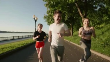 Nehir kenarında eğitim gören üç çok ırklı genç insan. Arkadaşlar birlikte vakit geçiriyorlar. Kızlar ve erkek sabah parkta süratle koşuyorlar. Açık havada antrenman yapan adamlar. Sağlık kavramı.