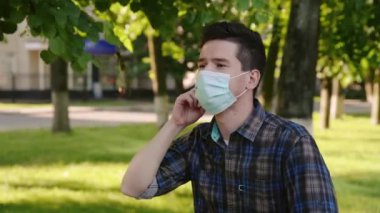 Genç adam koruyucu maskeyi yüzünden çıkarıp derin ve özgürce nefes alıyor. Adam karantinadan sonra parkta tek başına oturuyor. Coronovirüs veya covid-19 'dan sonra yeni bir yaşam tarzı. Sosyal uzaklık.