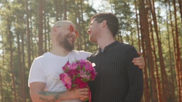 Két férfi virágcsokorral, gyűrűvel az ujján mosollyal és öleléssel. Meleg esküvői koncepció. Egy homokos pár portréja, akik boldogok együtt. Kapcsolati célok. LMBTQI, Pride Event, LMBT Pride Hónap, Meleg Büszkeség Szimbólum