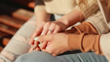 LGBT Gurur Ayı, Gay Onur Sembolü. Dışarıda oturan iki lezbiyen kızın ellerini kapayın. Değer veren genç bir kadın kız arkadaşına ya da karısına destek oluyor..