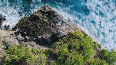 Deniz gelgitlerinin kayalıklara çarpması için muhteşem bir manzara. Gök mavisi deniz dalgaları, bol köpüklü kayalar ve ağaçlarla dolu inanılmaz tropikal doğa. Doğal güçlerin gösterimi. Seyahat kavramı.