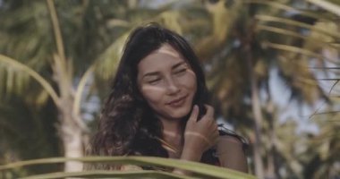 Tropik yaprakların içinde kusursuz pürüzsüz cilde sahip genç ve güzel bir kadının portresi. Doğal kozmetik ve cilt bakımı. Canon kamerasında 12 bit renk derinliğinde çekim.