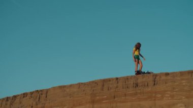 Seksi kız uçurumun kenarından kum kayağı ya da snowboard 'a binmeye hazırlanıyor. Sarışın, yolculuktan önce gemide kilit hazırlıyor. Spor, eğlence, risk, aşırı, yaz.