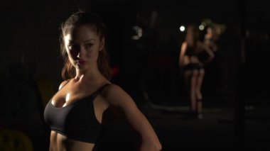 Atletik genç seksi kadın aynanın önünde vücut spreyliyor. Spor salonunda vücut geliştirme yarışmasına hazırlanırken gülümseyen güzel bir kadın. Spor, sağlık, yaşam tarzı kavramı.