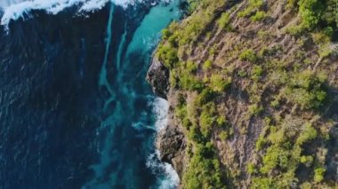 Seyahat kavramı. Deniz gelgitlerinin kayalıklara çarpması için muhteşem bir manzara. Doğal güçlerin gösterimi. Şaşırtıcı. Gök mavisi deniz dalgalı tropikal doğa, bol köpüklü ve ağaçlı kayalar..