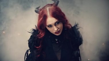 Okültizm ya da esrarengiz kavram ayini. Siyah boynuzlu kızıl saçlı cadı mum ışığında oturmuş ve elleri bağlı dua ediyor. Büyücülük yapan korkunç bir iblis. Cadılar Bayramı Gizemi.