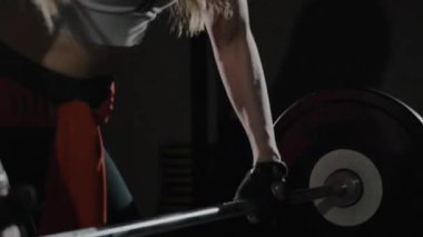 Atletik güzel kadın halterle egzersiz yapıyor. Güzel bir kız spor yapıyor, vücut geliştirme eğitimi alıyor, harika bir duruş ve kas gösterisi sergiliyor. Sağlık, yaşam tarzı, güzellik ve uyum kavramı