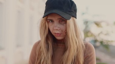 Yüzünde yara izi olan genç bir kadın portresi. Ev şiddeti kurbanı. Çaresizlik içindeki korkmuş kız şapkasının altında saklanan yarasından utanıyor. Küfürbaz aile ilişkisi ve suç kavramı. Sosyal sorun.