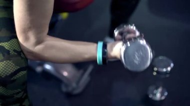 Halterleri kaldıran orta yaşlı kadının yakın plan kolları. Otuz yaşındaki bayan, beden eğitimi dersinde. Spor salonunda spor yapan aktif bir kadın. Spor ve spor yapan bir kadın. Boş zaman konsepti.