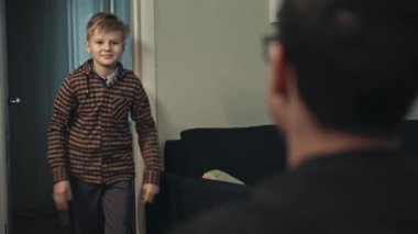 Genç baba sonunda işten eve geliyor. Babasına koşan ve ona sarılan sıradan giysili mutlu ergen oğlanın yakın çekimi. Gülümseyen oğul, akşam babasını kapıda karşılıyor. Mutluluk kavramı.