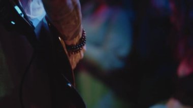 Canlı performans sırasında müzisyenlerin gitarına yakın çekim. Gençler kalabalığının önünde grup takılıyor. Küçük bir kulüpte müzik gösterisi, özgürlük ve coşku ortamı. Boş zaman kavramı, yaşam tarzı.