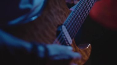 Konser sırasında solo çalan gitarist ellerinin yakın çekimi. Gitarda hızlı enerjik riffler yapan yetenekli bir müzisyen müzik şovunda orkestrayla şarkı söylüyor. Gençlik, gece hayatı ve özgürlük..
