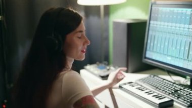 Gitar çalan ve sentezleyen genç bir kadın eşitleyici programı kullanarak müzik yaratıyor. Ev kayıt stüdyosunda bayan müzisyen şarkısı.