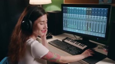 Gitar çalan ve sentezleyen genç bir kadın eşitleyici programı kullanarak müzik yaratıyor. Yaratıcılık sürecinin tadını çıkaran bir kız. Ev kayıt stüdyosunda hafif sinemada bayan müzisyen şarkısı.