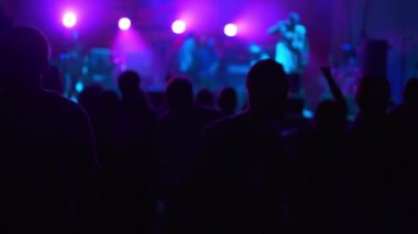 Hayranları ve yıldızları olan bir gece kulübünde canlı performans. Eğlence ve geçmiş kavramı. İnsanlar ellerini kaldırıp şarkı söylüyorlar. Rock grubu konserinde dans eden bir kızın silueti..