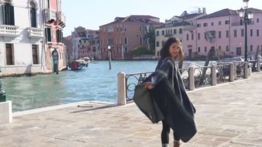 Venedik 'in dar sokaklarında yürüyen çizgili pançolu şık Asyalı kadın. Ateşli esmer tilki deniz kenarında romantik bir yürüyüş için işaret ediyor. Seyahat kavramı.