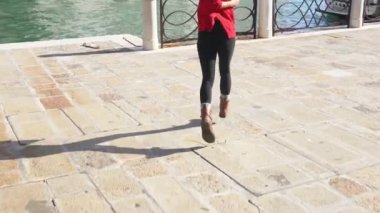 Ateşli esmer tilki deniz kenarında romantik bir yürüyüş için işaret ediyor. Venedik 'in dar sokaklarında yürüyen çizgili pançolu şık Asyalı kadın. Seyahat kavramı.