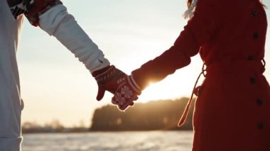 Noel zamanı randevuda olan iki kişi. Kış günbatımında eldiven takan çiftin arka görüntüsü. Aşk ve ilişki kavramı.