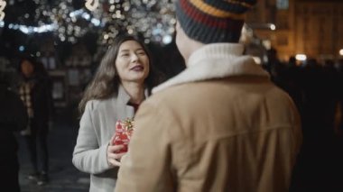 Kameraya geri çekilen bir adam, kız arkadaşına Noel hediyesi sunar, ama kız bundan hoşlanmaz. Başarısızlık, noel, yeni yıl, tatil konsepti. RED kamera, 10 bit klonlama