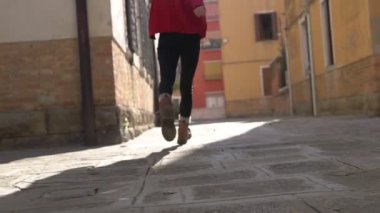 Venedik 'te parlak gün ışığında ilham arıyorum. Enfes, genç Asyalı, şık, kırmızı bir süveter giyen, antik dar sokaklar boyunca uzun bir geçmişi olan, yürüyen ve dönen bir kadının arka görüntüsü..