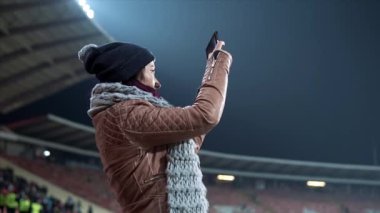 Bir fanatik kız bir maçın fotoğraflarını çekiyor.