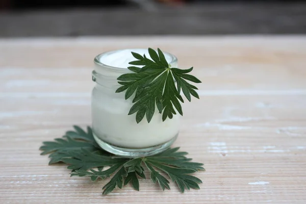 Cosmética ecológica. Crema con hojas verdes en el fondo de las tablas . —  Fotos de Stock