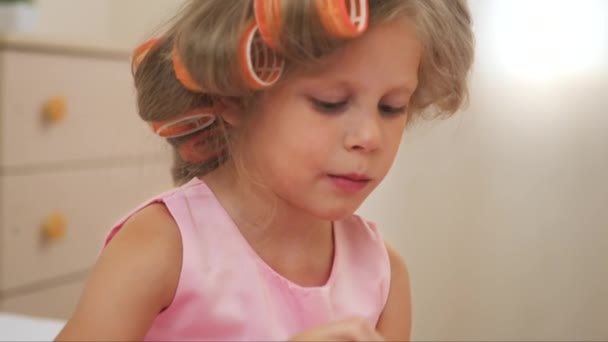漂亮的女孩在卷做指甲 粉红色礼服的小公主画钉子坐在床上 — 图库视频影像