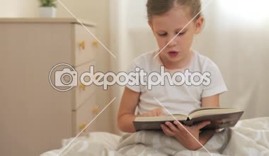 Güzel kız sabah yatağında oturup kitap okuma. Yaşam tarzı ve çocukluk kavramı.