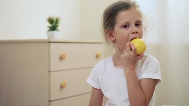 Χαριτωμένο Μικρό Κορίτσι Τρώει Κίτρινο Μήλο Στην Κρεβατοκάμαρα Πρωί Υγιεινά — Αρχείο Βίντεο