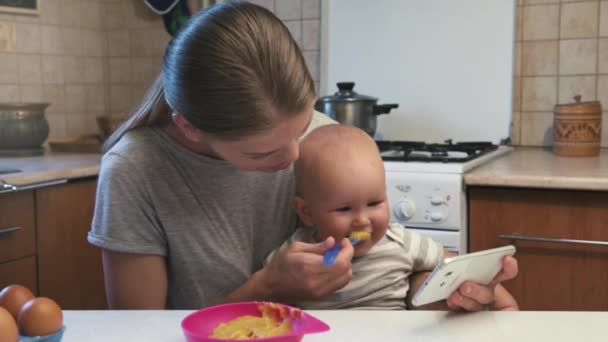 Young Mum Feeding Her Baby Girl Talking Phone Home — Stock Video