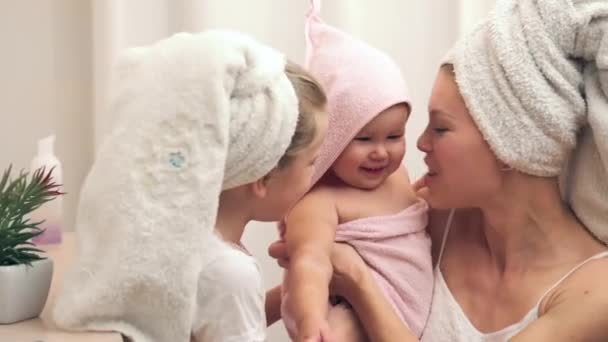 漂亮的女人和两个女儿洗完澡后裹在毛巾里 母亲和姐姐亲吻女婴 — 图库视频影像
