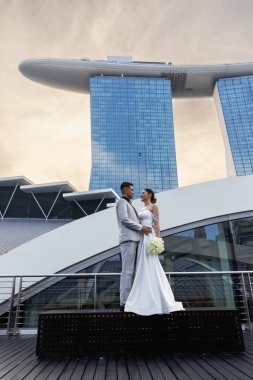 Gelin ve damat, Singapur şehrinin arka planına karşı. Güneşin doğuşu düğün fotoğrafı. - Evet. Yüksek kalite fotoğraf