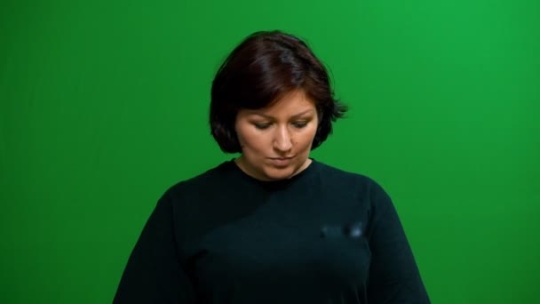 Young cute brunette is looking at the camera. The facial expression is thoughtful. He looks around himself. Background green screen. — Stock Video