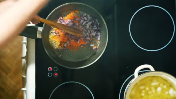 Primer plano de una mano haciendo una sopa casera con champiñones. Las zanahorias y cebollas en rodajas se fríen en una sartén . — Vídeo de stock