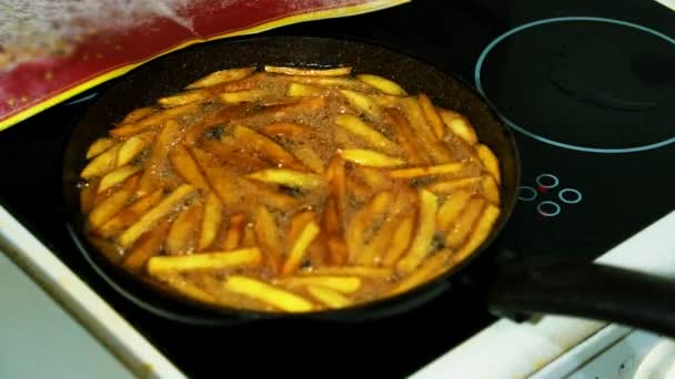 Preparação de batatas fritas caseiras. Assar as batatas picadas em uma frigideira em grandes quantidades de manteiga . — Vídeo de Stock