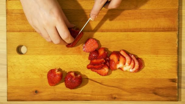 Snijden aardbeien in de keuken. Lichte houten tafel. — Stockvideo