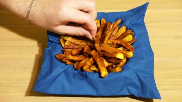 Patatine fritte in una tazza con un tovagliolo blu. Cerca di divertirti. Tavolo giallo legno . — Video Stock