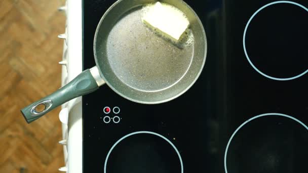 Στο τηγάνι με τη λαβή θερμαίνεται σε μια ηλεκτρική κουζίνα. Θέτουμε ένα κομμάτι βούτυρο να λιώσει. — Αρχείο Βίντεο