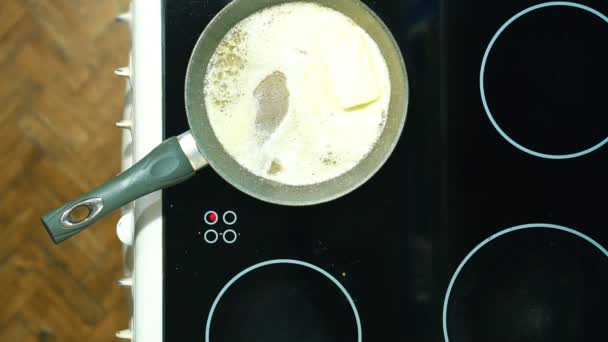 Τήξη ένα κομμάτι από το βούτυρο σε ένα τηγάνι με μια λαβή. Ανακατεύουμε για την πρόληψη της κολλώδους. — Αρχείο Βίντεο