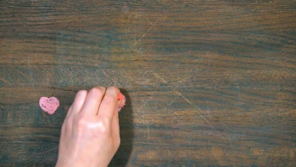 Closeup ruka kreslí na dřevěném prkénku. Postavy ze srdce. — Stock video