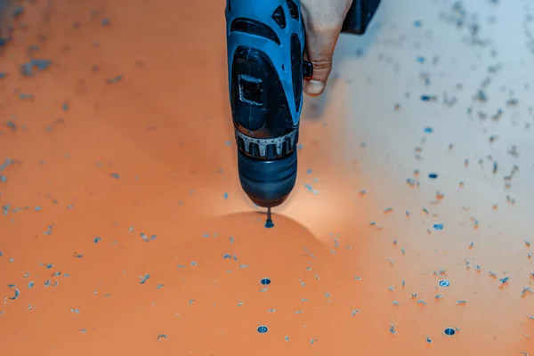 Closeup of a hand with an electric drill. The process of making holes in a plastic part. — Stock Photo, Image