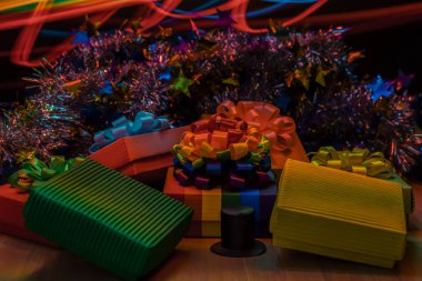 Ahşap masa üzerinde hediye kutuları vardır. Noel tinsel merkezi olan bir çizgili bir gökkuşağı bayrağı Lgbt. mavi, sarı ve kırmızı çizgiler bulanık.