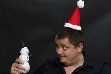 Noel şapka içinde genç bir adam. Kardan adam elinde.