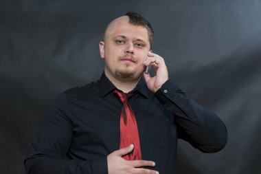 Serseri bir cep telefonu ile. Konum için objektif yönlendirilir. Ciddi ve memnun yüzüdür. Sağ eliyle dokunduğu kravatını kumaş.