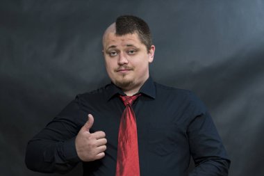 Serseri. Kırmızı kravat. Sağ el başparmak yukarı doğru yönlendirilir. İfade yüzler ironik ve olumlu.