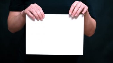 Eller closeup kağıt bir renk arka plan üzerinde bir levha ile. Eller arasında beyaz kağıdın gözyaşı.