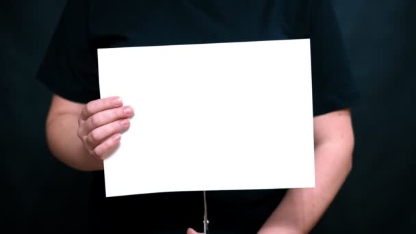 Primer plano de las manos con una hoja de papel. Tijeras una hoja de papel blanco a través de . — Vídeos de Stock