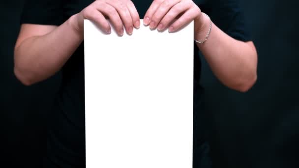 Closeup of hands with a sheet of paper. Tears a sheet of white paper in length. — Stock Video