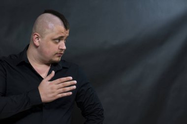 Siyah gömlekli bir mohawk ile punk. El için muhatap işaret eder. Yüz ifadesi iddialı.